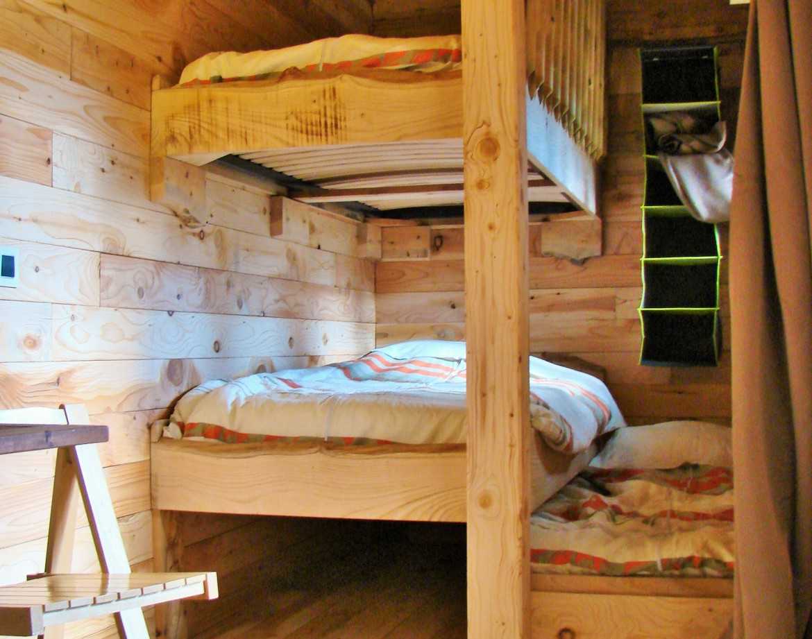 Cabane en bois avec lits superposés, ambiance chaleureuse et naturelle.