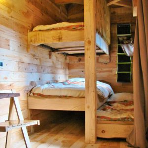 Cabane en bois avec lits superposés, ambiance chaleureuse et naturelle.