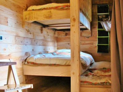Cabane en bois avec lits superposés, ambiance chaleureuse et naturelle.