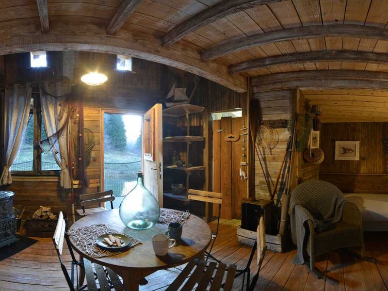 Chalet en bois chaleureux avec un coin salon et une cuisine rustique.