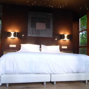 Chambre moderne en cabane avec vue sur la nature et éclairage étoilé.