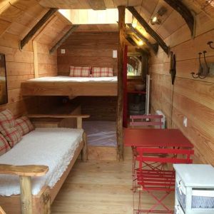 Hébergement insolite en tonneau en bois, avec lit superposé et décoration chaleureuse.