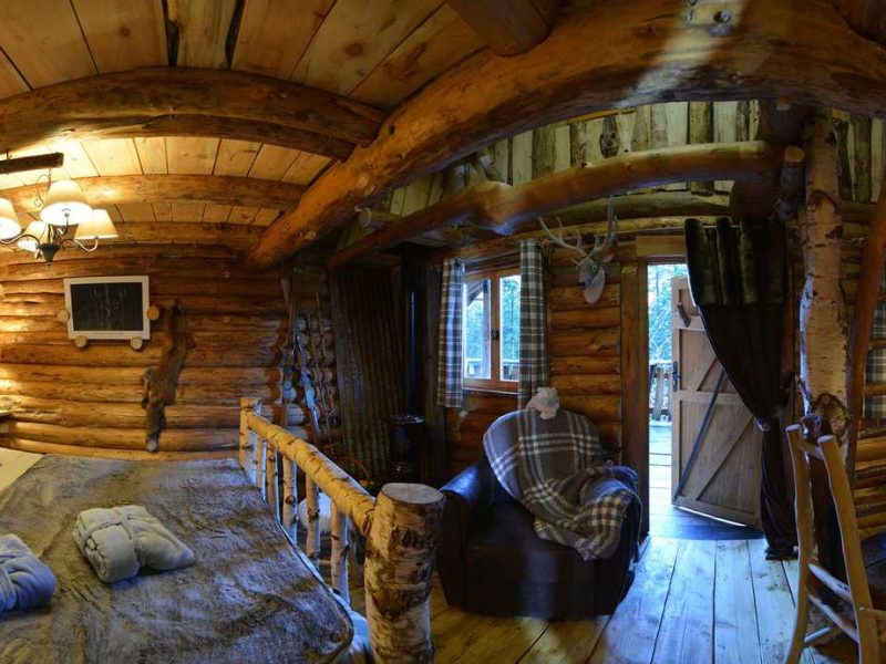 Chalet en bois avec lit douillet et coin repas chaleureux. Ambiance rustique et accueillante.