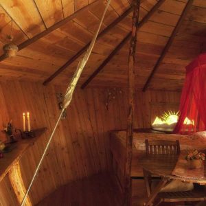 Cabane en bois cosy avec lit à baldaquin et ambiance chaleureuse.