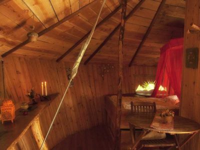 Cabane en bois cosy avec lit à baldaquin et ambiance chaleureuse.