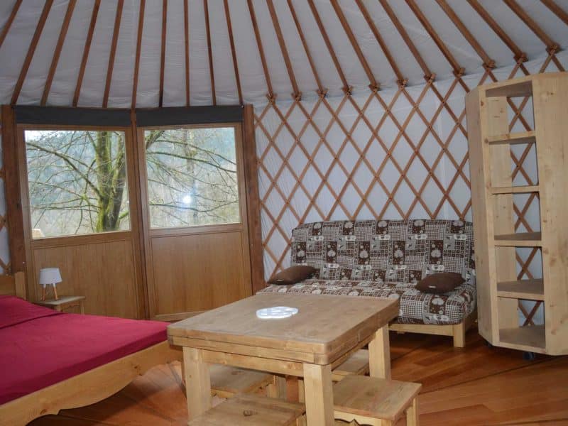 Yourte confortable avec un intérieur en bois et un coin salon accueillant.