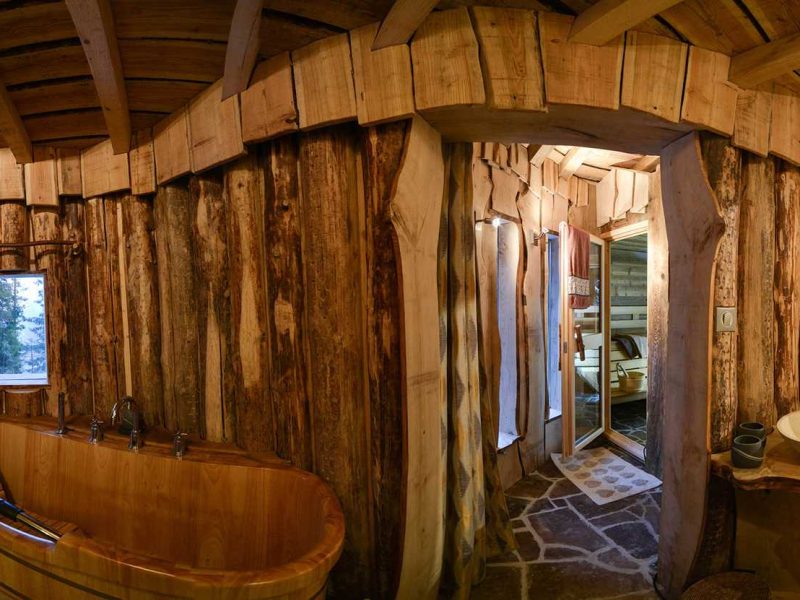 Cabane en bois avec baignoire en bois et murs rustiques en rondins.