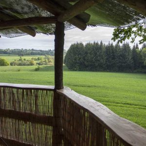 Cabane perchée en Auvergne avec vue panoramique sur des champs verdoyants.