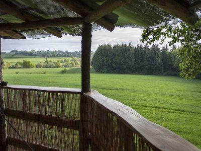 Cabane perchée en Auvergne avec vue panoramique sur des champs verdoyants.