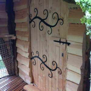 Cabane en bois en Bourgogne avec une porte sculptée et des détails en fer forgé.