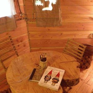 Cabane en bois en Bourgogne, intérieur chaleureux avec table en tronc et décor féerique.
