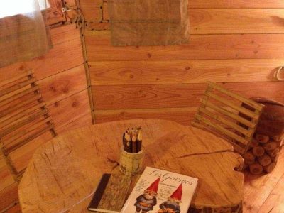 Cabane en bois en Bourgogne, intérieur chaleureux avec table en tronc et décor féerique.