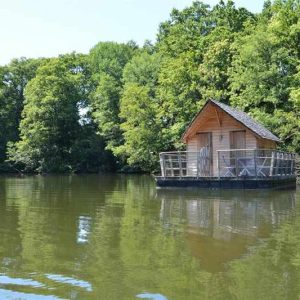 Cabane flottante au Pays de la Loire, entourée de verdure et reflétée dans leau.