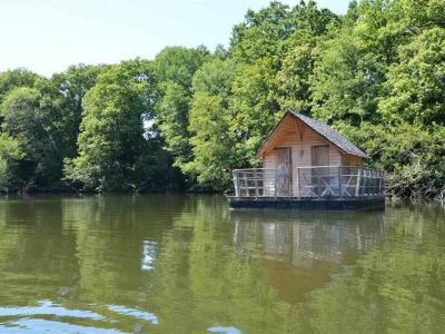 Cabane flottante au Pays de la Loire, entourée de verdure et reflétée dans leau.
