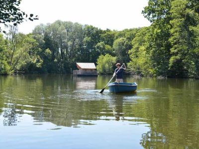 Cabane flottante dans les Pays de la Loire, vue paisible sur un lac verdoyant.