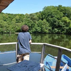 Cabane flottante au bord dun lac, entourée de verdure paisible.