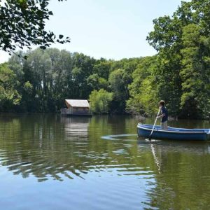 Cabane flottante à Pays de la Loire, entourée de verdure, vue depuis un canoë.
