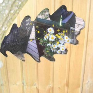 Cabane perchée en bois avec un miroir en forme de feuille et des fleurs reflétées.