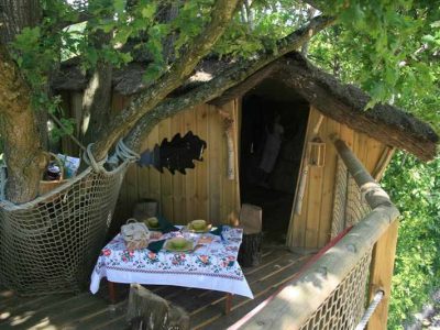 Cabane dans les arbres en Pays de la Loire, avec une table décorée sous les feuillages.