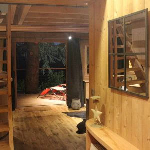 Hébergement insolite en bois avec une vue sur la nature et un escalier en colimaçon.