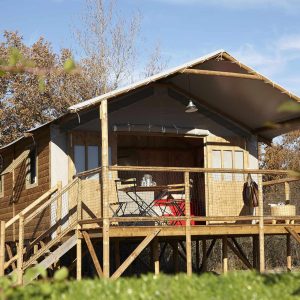 Cabane sur pilotis en Auvergne, avec terrasse en bois et vue sur la nature.