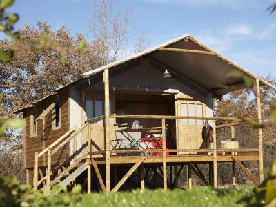 Cabane sur pilotis en Auvergne, avec terrasse en bois et vue sur la nature.