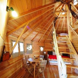 Cabane en bois à Bourgogne, intérieur chaleureux avec meubles en bois et mezzanine.