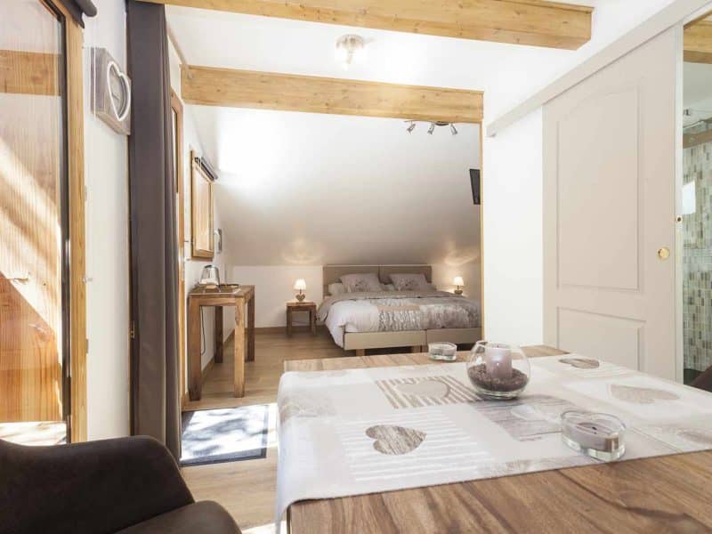 Chalet cosy avec lit double, lumière naturelle et décoration en bois chaleureux.