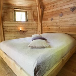 Cabane en bois cosy avec lit douillet et ambiance chaleureuse en Auvergne-Rhône-Alpes.