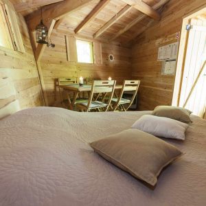 Cabane en bois chaleureuse avec lit douillet et coin repas lumineux.