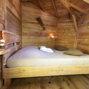 Chalet en bois chaleureux avec lit douillet et ambiance lumineuse apaisante.