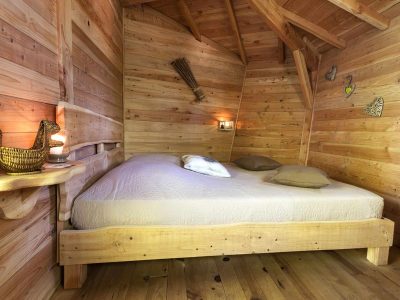 Chalet en bois chaleureux avec lit douillet et ambiance lumineuse apaisante.