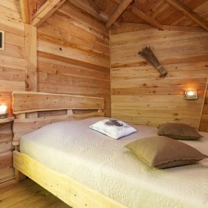 Chalet en bois chaleureux avec lit douillet et décor naturel en Auvergne-Rhône-Alpes.