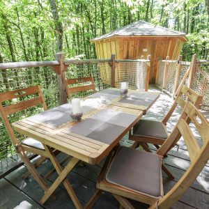 Cabane dans les arbres en Auvergne-Rhône-Alpes, avec une terrasse en bois et des chaises