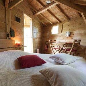 Chalet en bois cosy avec lit douillet et coin repas lumineux.