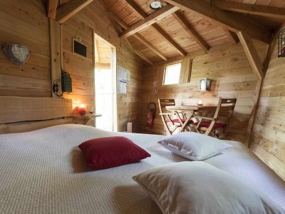 Chalet en bois cosy avec lit douillet et coin repas lumineux.