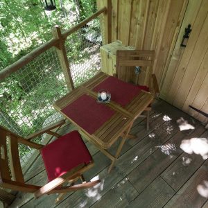Cabane perchée en Auvergne-Rhône-Alpes avec une terrasse en bois et chaises confortables.