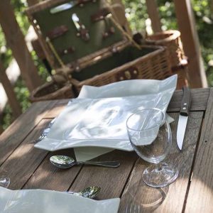 Table élégante en bois avec vaisselle, près dun hébergement insolite en pleine nature.