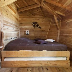Chalet en bois chaleureux avec lit double et décoration naturelle. Parfait pour un séjour cocooning.