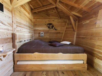 Chalet en bois chaleureux avec lit double et décoration naturelle. Parfait pour un séjour cocooning.