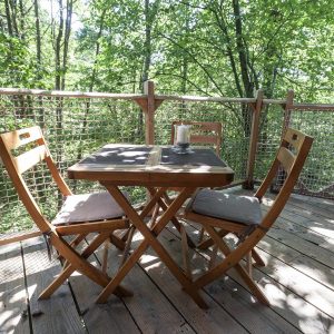 Cabane perchée en Auvergne-Rhône-Alpes avec terrasse en bois et vue sur la forêt.
