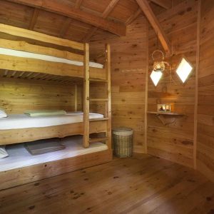 Chalet en bois avec lits superposés, ambiance chaleureuse et décor naturel.