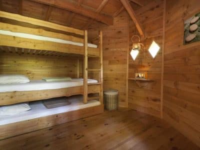Chalet en bois avec lits superposés, ambiance chaleureuse et décor naturel.