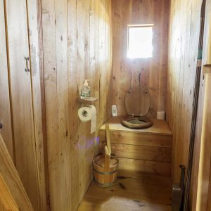 Toilettes en bois dans un hébergement insolite en Auvergne-Rhône-Alpes. Ambiance chaleureuse.