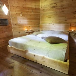 Chalet en bois chaleureux avec lit douillet et ambiance tamisée. Parfait pour un séjour romantique.
