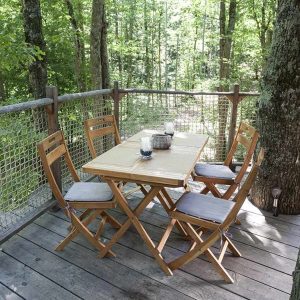 Table en bois sur une terrasse en hauteur, entourée darbres en Auvergne-Rhône-Alpes.