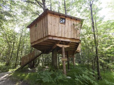Cabane dans les arbres en Auvergne-Rhône-Alpes, perchée au milieu de la verdure.