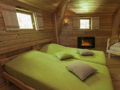 Chalet en bois avec lits douillets et cheminée, ambiance chaleureuse en Auvergne.