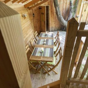 Cabane dans les arbres en Auvergne-Rhône-Alpes avec une table en bois et vue sur la nature.