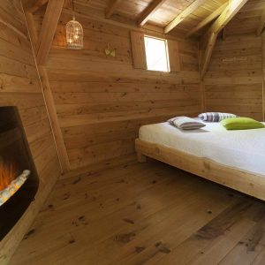 Cabane en bois chaleureuse avec lit douillet et cheminée moderne.